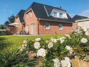 a brick house with white roses in the yard at Kleine Flucht in Tating