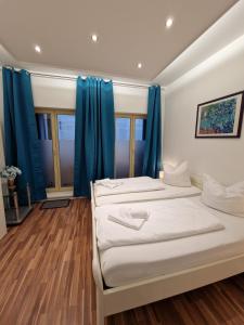2 Betten in einem Zimmer mit blauen Vorhängen in der Unterkunft Altstadt-Apartment Rothenberg in Wernigerode