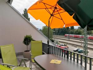 een tafel en stoelen op een balkon met een trein bij Ferienwohnung Urlaubsglück- lichtdurchflutete Wohnung mit Balkon und Seesicht in Lindau