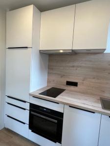 a kitchen with white cabinets and a black oven at Dünen Lodge 4 in Juist