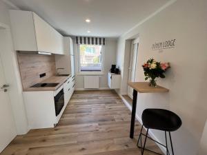 a kitchen with white cabinets and a table and a vase of flowers at Dünen Lodge 1 in Juist +3 photos