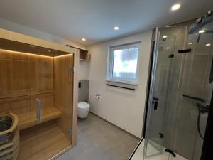 ein Bad mit einer Dusche, einem WC und einem Fenster in der Unterkunft Dünen Lodge 1 in Juist
