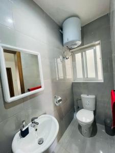 W łazience znajduje się umywalka, toaleta i lustro. w obiekcie Coral Cove Comfort Apartment Room 3 w mieście St Paul's Bay