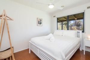 a bedroom with a white bed and a window at Ocean Spray Retreat in Port Fairy