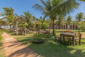 a resort yard with tables and chairs and palm trees at Pousada Katavento #Q2 - Suíte Dupla por Carpediem in Cumbuco