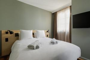 Un dormitorio con una cama blanca con toallas. en La Loge Gogaille - 7 Dormants - Accès autonome en Orléans
