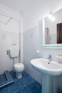 a white bathroom with a sink and a toilet at Kentrikon Rooms in Limenaria