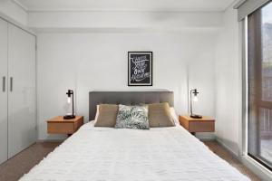 a bedroom with a large white bed with two lamps at Apartment 12 Pacific Apartments in Lorne