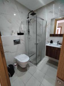 a bathroom with a shower and a toilet and a sink at Luxueux S1 Mourouj 6 in Nassene Srhira