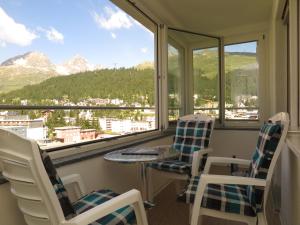 Un balcón con mesa y sillas y montañas. en Ova Cotschna 705, en St. Moritz