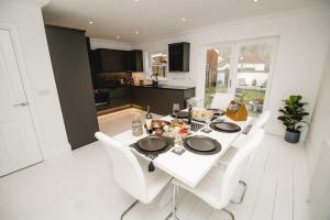 a white dining room with a white table and white chairs at Brand New Stylish Three Story House! in Thorpe Saint Andrew