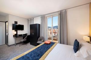 a hotel room with a bed and a desk and window at Best Western Plus Hôtel Massena Nice in Nice