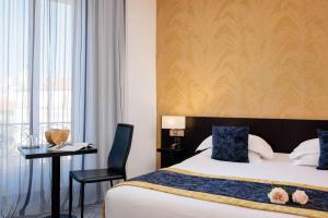 a bedroom with a bed and a desk with a chair at Best Western Plus Hôtel Massena Nice in Nice