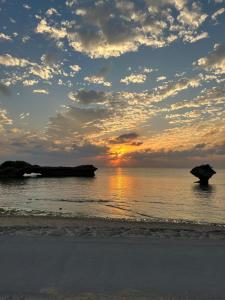 a sunset on the beach with an umbrella at ライフタイムハウス55 in Furugen