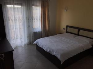 a bedroom with a bed with white sheets and curtains at VILA DE PE DEAL in Poiana Stampei