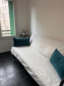 ein weißes Bett mit zwei blauen Kissen in einem Zimmer in der Unterkunft Joli app. lumineux gare st Charles in Marseille