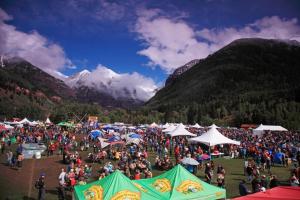 een grote menigte mensen in een veld met bergen bij Cozy Condo steps to Coonskin lift in Telluride +4 foto's