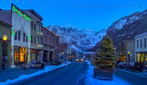 a christmas tree on a street in a town with mountains at Cozy Condo steps to Coonskin lift in Telluride