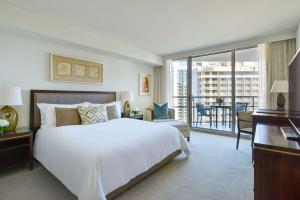 a bedroom with a large white bed and a balcony at Ka La'i Waikiki Beach, LXR Hotels & Resorts in Honolulu