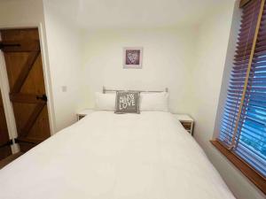 1 dormitorio con cama blanca y almohada en Little Knapp Cottage, East of Church Road, Chichester, West Sussex PO19 7YH, en Chichester
