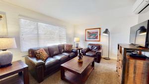 a living room with a leather couch and a table at Downtown Cozy Home Base - Purple Sage 3 in Moab