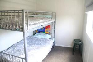 ein kleines Schlafzimmer mit einem Etagenbett und einem Stuhl in der Unterkunft Quiet, Private and Central in Tairua