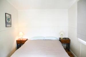 a bed in a room with two nightstands and two lamps at Quiet, Private and Central in Tairua