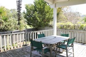 a wooden table and green chairs on a porch at Quiet, Private and Central in Tairua