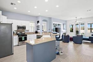 uma grande cozinha e sala de estar com armários e eletrodomésticos brancos em Luxurious Getaway Near Coachella Stagecoach Pool Putting Green Parking Firepit Sleeps 11 em Indio