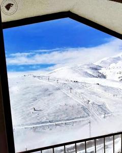 Popova Shapka的住宿－Villa Winterfell Popova Shapka，从雪覆盖的山窗上可欣赏到风景
