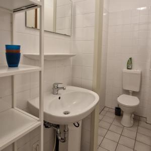 a white bathroom with a sink and a toilet at Ferienwohnung Strandmuschel in Kühlungsborn
