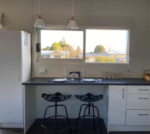 a kitchen with a counter with two stools and a window at Haven On Tau in Ohakune
