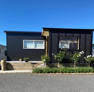 a black house with some plants in front of it at Haven On Tau in Ohakune