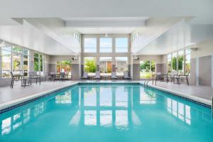 a swimming pool with tables and chairs in a building at Residence Inn by Marriott New Haven Hamden in Hamden