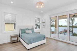 Dormitorio blanco con cama y ventana grande en Infinity Pool Paradise I Luxe Waterfront Living, en Edgewater