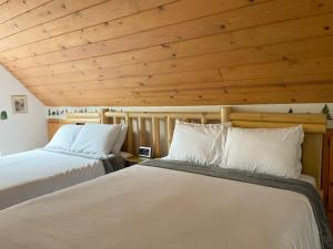 2 bedden in een kamer met houten plafonds bij A-Frame Cabin in The Sequoias in Wofford Heights