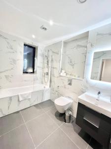 a bathroom with a toilet and a tub and a sink at Queens Luxury Apartments Wembley Stadium - London in London