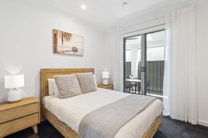 a white bedroom with a bed and a balcony at Belle Escapes - Golf Villa by the Sea in Grange