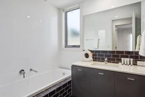 a bathroom with a sink and a tub and a mirror at Belle Escapes - Golf Villa by the Sea in Grange