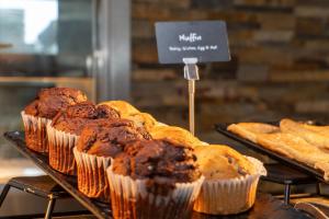 a bunch of muffins on display in a bakery at Aloft London Excel in London