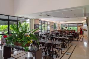 un ristorante con tavoli, sedie e piante di Suítes Inside The Universe Paulista a San Paolo
