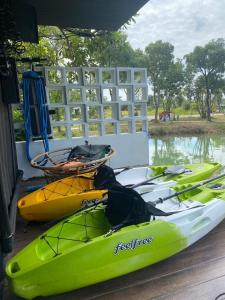 tres kayaks están estacionados en un muelle junto al agua en Little Farm Nakornnayok, 