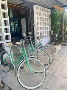 three bikes parked outside of a house with a dog at Little Farm Nakornnayok 