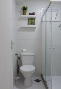 een witte badkamer met een toilet en een glazen douche bij Nomads apto a 1 quadra do mar, praia de itaparica in Vila Velha