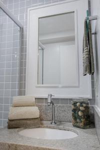 een badkamer met een wastafel, een spiegel en handdoeken bij Nomads apto a 1 quadra do mar, praia de itaparica in Vila Velha