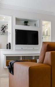 een woonkamer met een flatscreen-tv en een stoel bij Nomads apto a 1 quadra do mar, praia de itaparica in Vila Velha