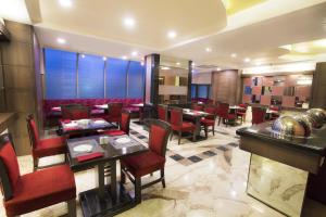 a restaurant with tables and chairs in a room at Hotel Airport International Mumbai in Mumbai