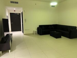 a living room with a black couch and a tv at Lodges in Al Ain