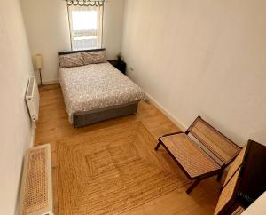 um pequeno quarto com uma cama e uma cadeira em Flat 6 Stay In Aldgate em Londres
