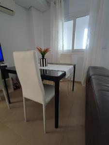 a dining table and a white chair in a living room at Hacienda Riquelme Golf Resort Ground Floor Apartment Sucina Murcia in Murcia